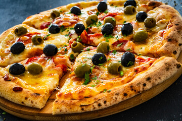 Circle pizza chorizo with black and green olives and mozzarella on wooden table
