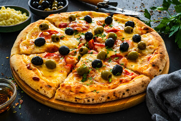 Circle pizza chorizo with black and green olives and mozzarella on wooden table
