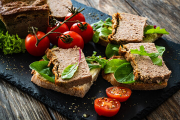 Tasty sandwiches with liverwurst and chive on wooden table
