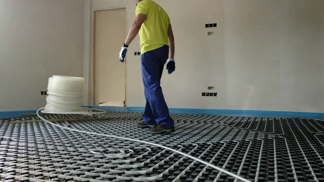 Man installs and checks underfloor heating, man installing plastic pipes