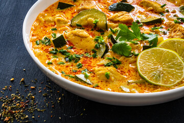 Curry soup with chicken meat, zucchini and vermicelli  noodles on black background
