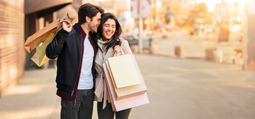 A couple walking down the street while holding shopping bags, enjoying a day out together.