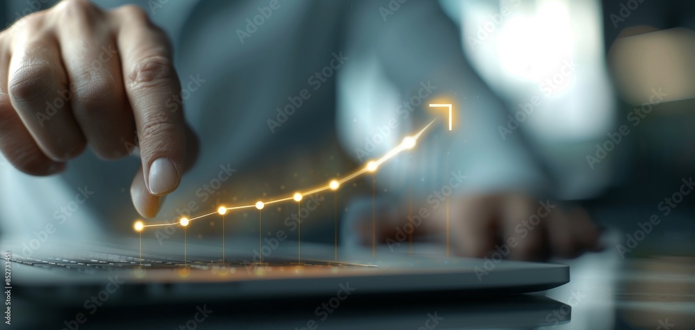 Aufkleber Using a laptop, a businessman points to a virtual graph with a rising arrow, illustrated with a rising sun light effect on a dark background, representing the concept of business advancement.