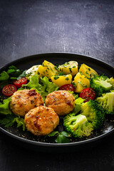 Cooked meatballs, boiled broccoli, boiled potatoes and fresh vegetables on wooden table
