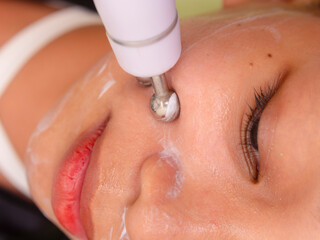 Fototapeta premium Close-up of a person's face undergoing a microcurrent facial therapy at a beauty clinic, highlighting skincare treatment and facial rejuvenation.