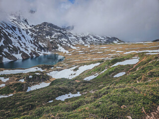 Snowy Mountain Landscape with Small Lake and Low-Hanging Clouds