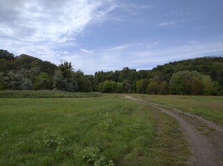 View of a mountain with trees growing on it. Below the mountain there is a plain - lakes and a river.