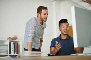 Men, designer and computer at table for talking, development and collaboration in office. Partners,...