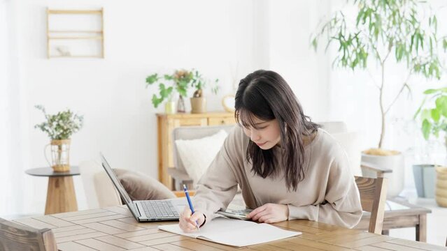 電卓で計算してメモをする女性
