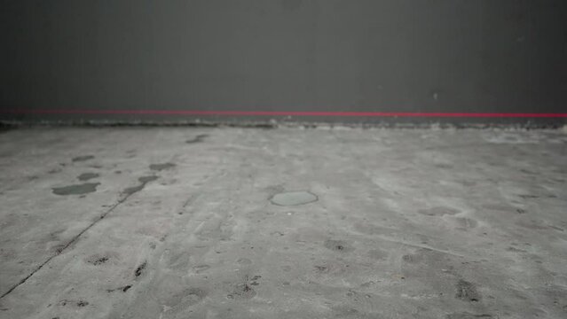 Laser construction level with red beams on the wall. Apartment renovation and construction work. Installation of a laser level for floor repair.