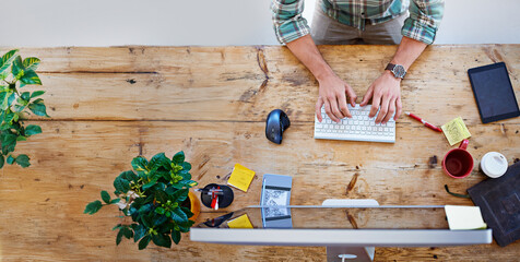 Top view, hands and business with man, computer and typing with keyboard, graphic designer and connection. Above, person and entrepreneur at desk, pc and internet with creative agency and consulting