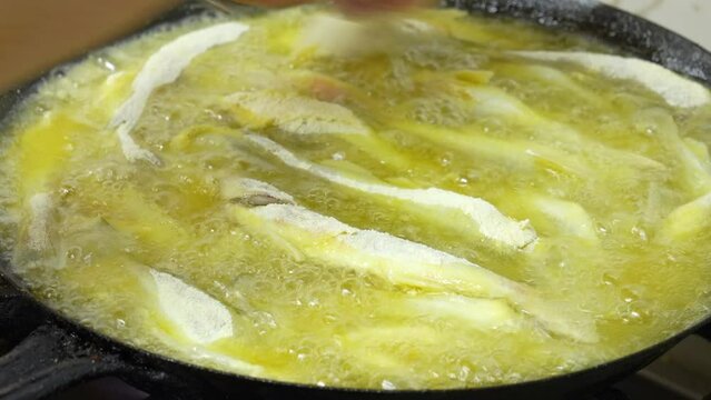 fish frying in oil in a pan, close-up