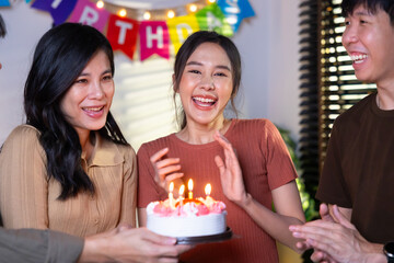 friend birthday cake. young asian woman blows out a birthday cake that friends brought for a birthday party. celebrating Birthday party. Group of friends smiling enjoying party