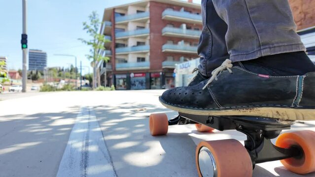 Person riding a small electric longboard through the city, focusing on wheels and feet. Urban sustainable and eco-friendly mobility. Zero emissions