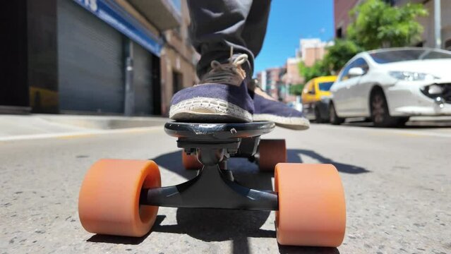 Person riding a small electric longboard through the city, focusing on wheels and feet. Urban sustainable and eco-friendly mobility. Zero emissions