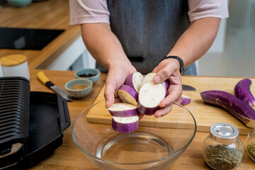 Chef at the kitchen preparing grilled eggplants with garlic