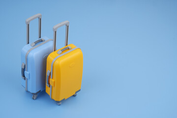 Orange and blue travel suitcase on blue background. Copy space for text.