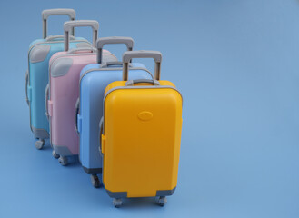 Four different colorful suitcases on blue background. Copy space for text. Travel and vacation concept.	