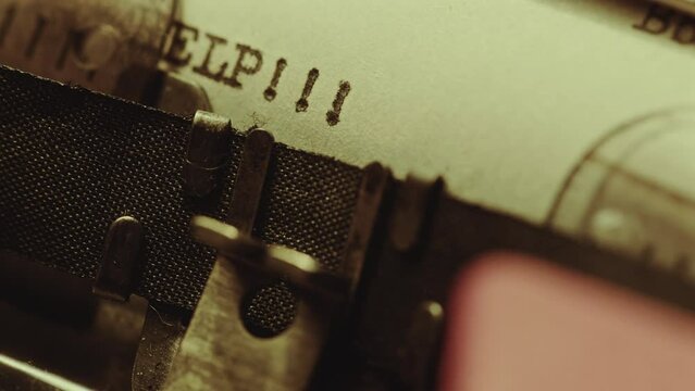 Retro typewriter printing word HELP with three exclamation points on paper page. Extreme close-up shot