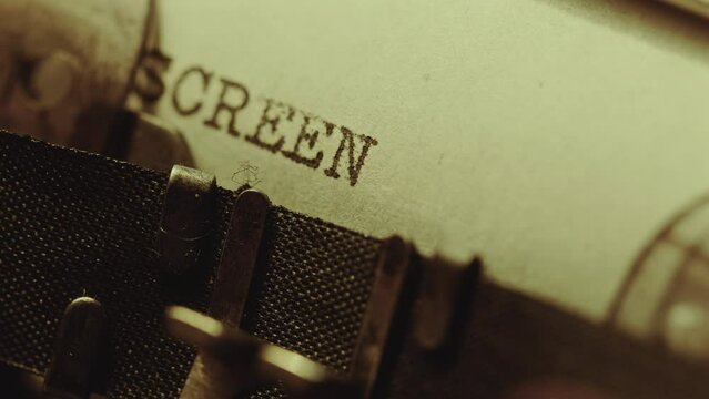 Typing Screenwriting word in upper case on paper page with retro analog typewriter. Extreme close-up view