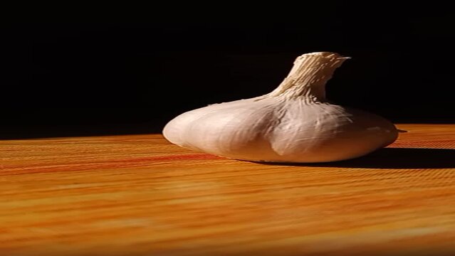 Moving a garlic on a table on a dark background. shot twisting garlic. herbs. Slowmotion. Vertical