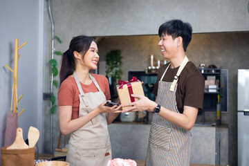 Beautiful young asian couple with gift box at home. Happy young man getting Saint Valentines Day.
