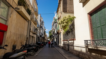 Quaint European street with pedestrians and lined with motorcycles on a sunny day, ideal for travel and lifestyle themes