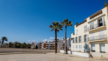 Fototapeta premium Sunny Mediterranean esplanade with white buildings and palm trees, evoking European summer holidays and Spanish coastal living
