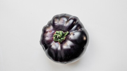 Freshly washed blue purple tomato with water droplets isolated on a white background, ideal for vegan recipes and healthy eating concepts