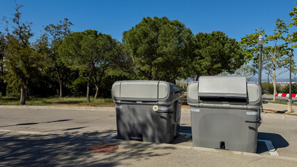 Two urban waste containers in a park, symbolizing recycling and environmental conservation, ideal...