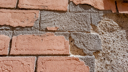 Close-up texture of a deteriorating pink brick wall, concept of urban decay and renovation, suitable for backgrounds and construction themes