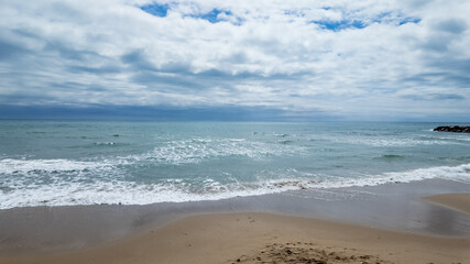 Serene beach landscape with gentle waves and cloudy sky, ideal for travel brochures and summer getaway promotions
