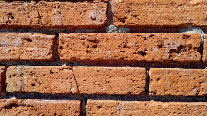 Close-up texture of red brick wall under natural sunlight, suitable for background, construction concepts, and Labor Day promotions
