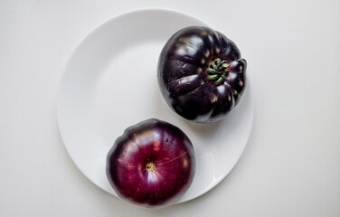 Farm-fresh purple blue  and heirloom tomato on a white plate, ideal for healthy eating, vegetarian recipes, and organic food concepts