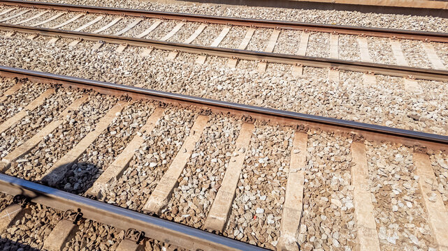 Diagonal view of parallel railroad tracks with wooden sleepers and crushed stone ballast, concept for transportation and travel industry