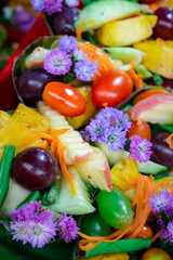 A colorful fruit salad with purple flowers on top