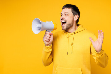 Young excited fun shocked man wears hoody casual clothes hold in hand megaphone scream announces...
