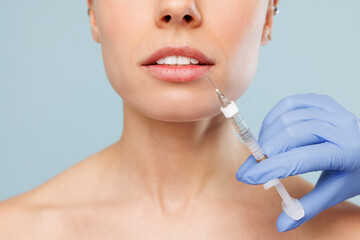 Close up cropped half naked topless Caucasian young woman with nude make up getting lip cosmetic...