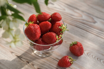 Top view of ripe strawberries in a glass bowl on a wooden table