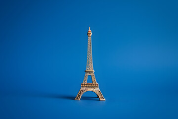 A close-up shot of a miniature Eiffel Tower on a solid royal blue background, capturing the charm of Paris 