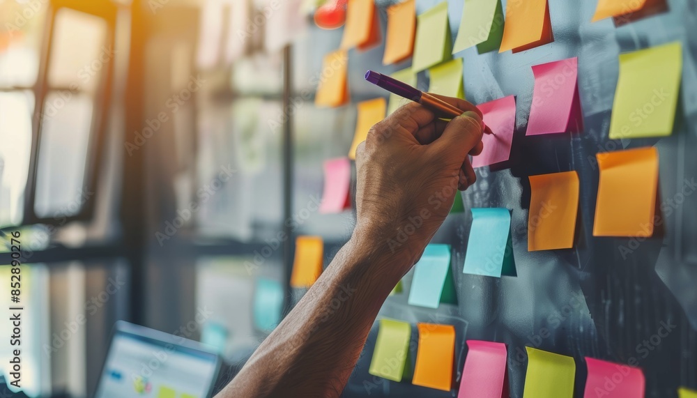 Poster businessman organizing task list on sticky note in modern office for efficient work planning