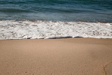 Detalhe de praia com areia não poluída e água em boas condições para banho e uso.