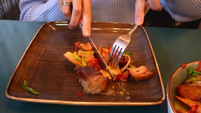 Traditional Georgian recipe Ojakhuri with pork and potatoes close-up. Female Hands Cutting Meat With Fork And Knife Potatoes On Plate Horizontal Top View Ojakhuri. Georgian cuisine,