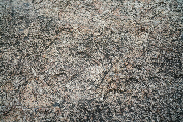 Close-up at rigid granite rock surface in brown and gray color tone with coarse textured.