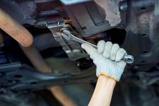 Close up hand of technician hold wrench to repair under car skrew in car garage.
