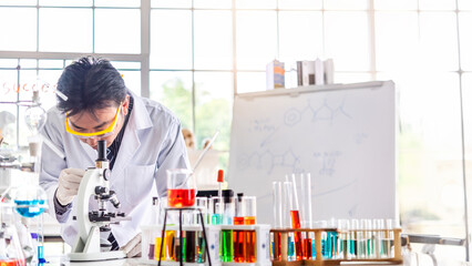 Attractive young Asian scientist man lab technician assistant analyzing sample in test tube at...