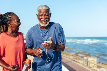 Senior African American couple laughing and listening to music on the coast