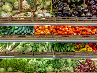 Vegetables of various kinds displayed in boxes on shelves in the greengrocer's shop, tomatoes and cabbage and colorful peppers and cabbage with eggplant and salads for sale