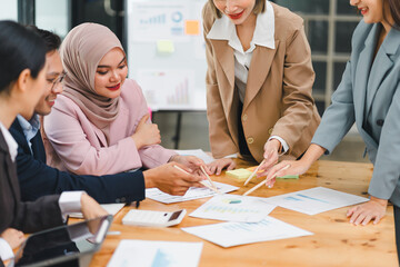 Diverse business team collaborates and analyzes reports during meeting, highlighting teamwork and strategic planning in modern office.