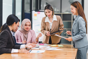 Diverse business team collaborates and analyzes reports during meeting, highlighting teamwork and strategic planning in modern office.